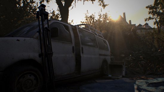 Een witte, vervallen bestelwagen staat met de deuren open in een bosrijke omgeving bij zonsondergang. Een statief staat ernaast.
