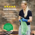 Vrolijke vrouw met blauwe handschoenen vult een groene, biologisch afbreekbare vuilniszak.