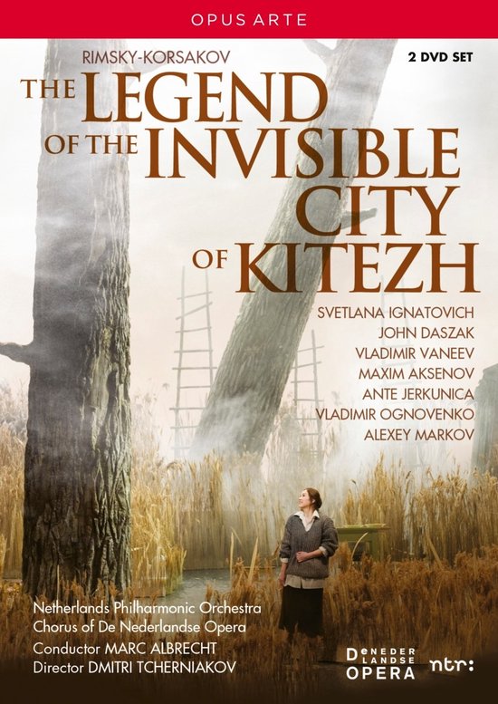 DVD hoes: Titel 'The Legend of the Invisible City of Kitezh'. Een vrouw in een rustieke jurk staat in een veld met droog gras, met op de achtergrond grote bomen en ladders. Watermerk: OPUS ARTE.