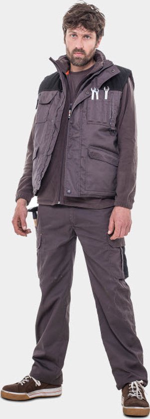 Man met donkergrijze bodywarmer, bruine trui en broek.
