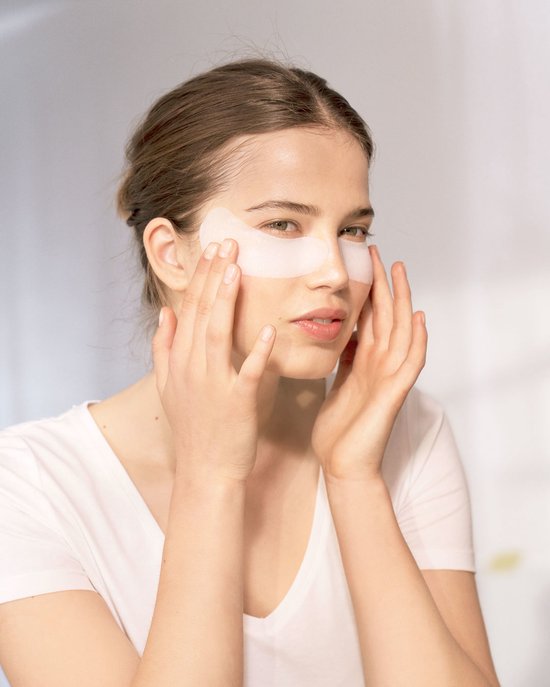 Jonge vrouw met witte Garnier Hydra Bomb oogmaskers onder haar ogen.