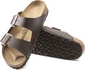 Bruine Birkenstock Arizona slippers met koperkleurige gespen en golvend zoolpatroon.