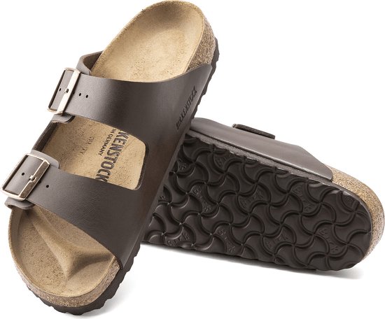 Bruine Birkenstock Arizona slippers met koperkleurige gespen en golvend zoolpatroon.