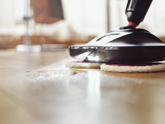 Zwarte Vileda Looper vloermop met draaiende rode en witte pads, sproeit water op een houten vloer.