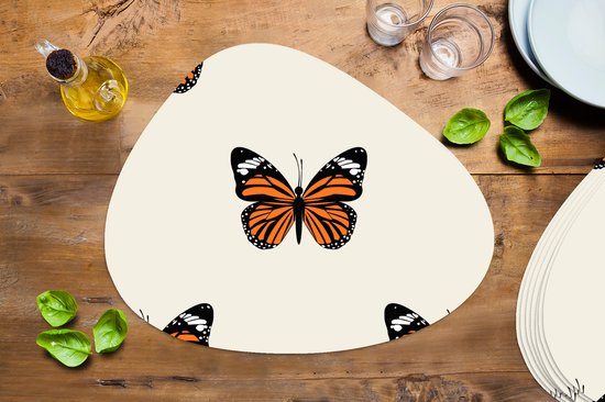 Crèmekleurige placemat met oranje vlinderprint, met glazen, bestek en groenten op een houten tafel.