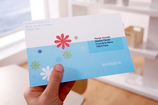 Carte d'invitation à motif floral, avec adresse, tenue par une main