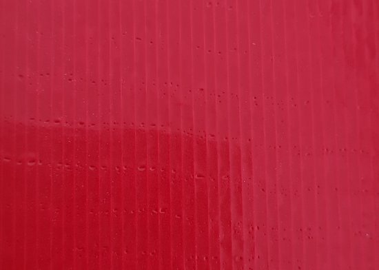 Textuur van rode ducttape met verticale ribbels en kleine waterdruppels.