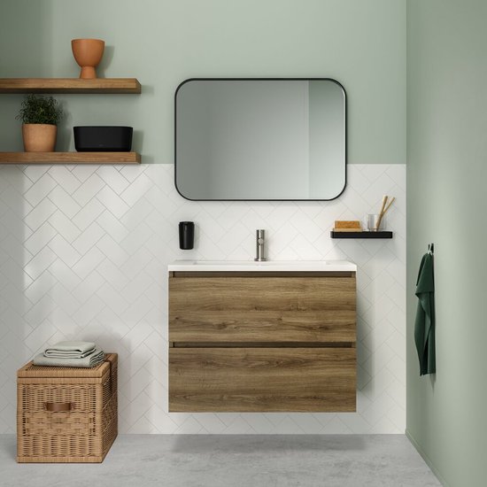 Salle de bain élégante avec meuble-lavabo en bois, miroir, accessoires noirs, serviette verte et panier en osier.