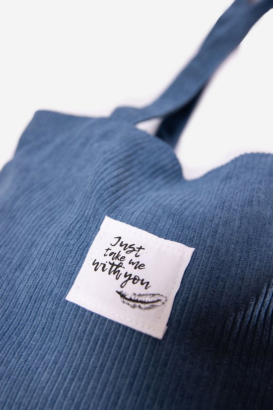 Détail d'un sac bleu en velours côtelé avec inscription et plume.