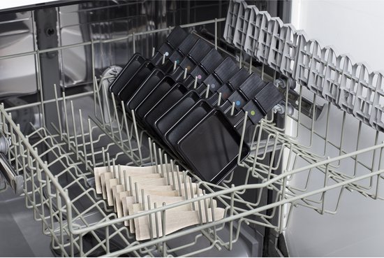 Vaatwasser rek met negen zwarte raclette-pannetjes en een stapel spatels.