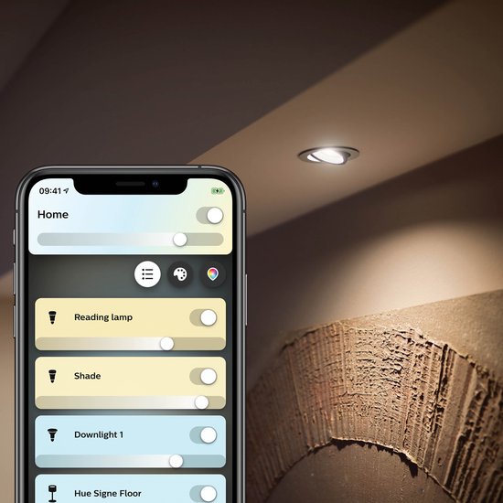 Smartphone met Philips Hue app, met een gedimd plafondlicht op de achtergrond.