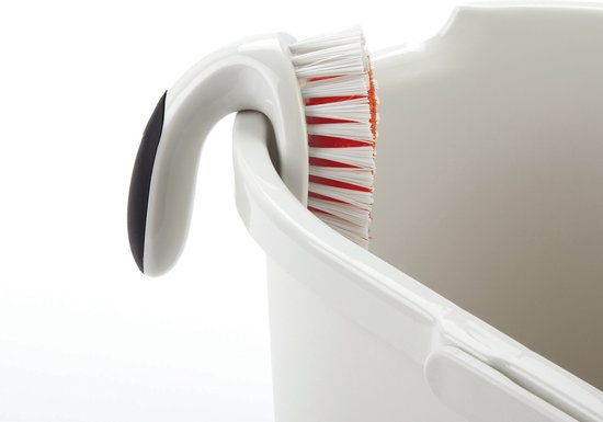 Brosse de nettoyage blanche avec poignée blanche et noire, posée dans une bassine blanche. Poils rouges visibles.