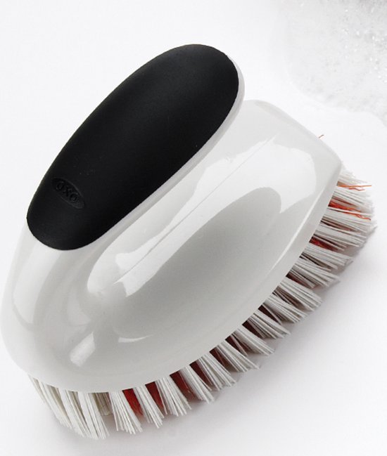 Brosse de nettoyage blanche avec poignée noire OXO et poils blancs à base rouge.