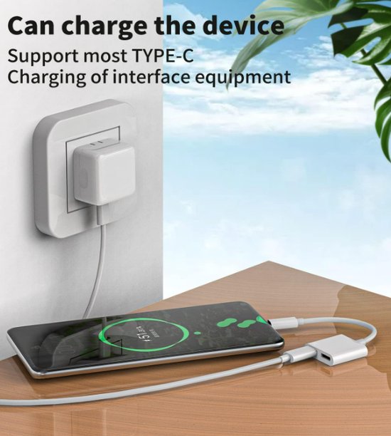 Een telefoon laadt op via een witte USB-C adapter met oplader, met planten op de achtergrond.