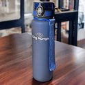 Donkerblauwe King Mungo drinkfles met gestreept blauw hengsel op een houten tafel.