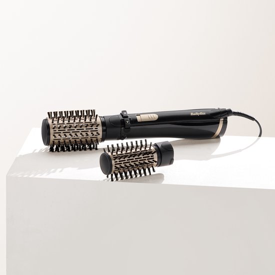 Zwarte BaByliss roterende föhnborstel met goudkleurige accenten, twee losse borstels ernaast.