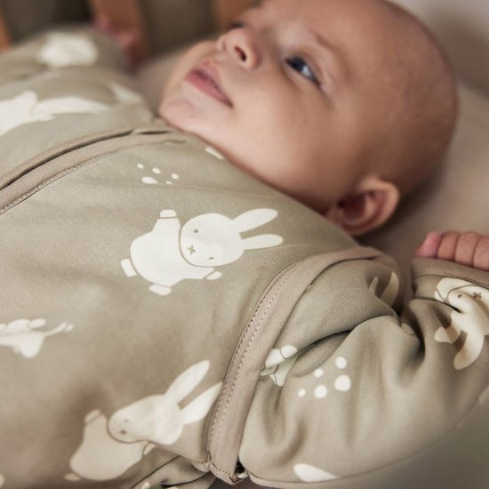 Close-up van een baby in een olijfgroene slaapzak met Miffy print.