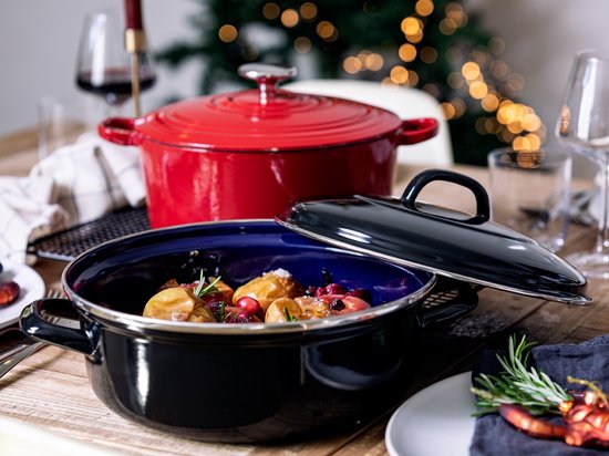 Zwarte braadpan met blauwe binnenkant, gevuld met aardappelen, veenbessen en rozemarijn. Zwart deksel ligt ernaast.
