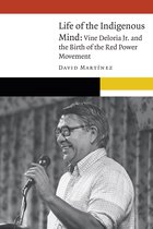 Boekcover met de titel 'Life of the Indigenous Mind: Vine Deloria Jr. and the Birth of the Red Power Movement' door DAVID MARTÍNEZ. Een portret van een lachende man met bril, die een microfoon vasthoudt.