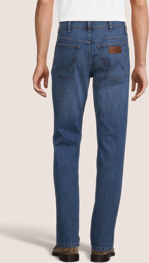 Blauwe Wrangler jeans met bruine leren logo patch op de achterkant.