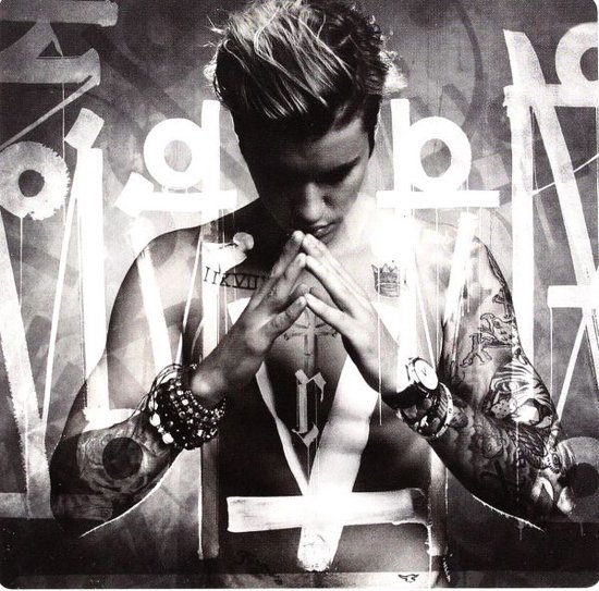 Justin Bieber met gevouwen handen en tatoeages, voor een achtergrond met graffiti.