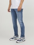 Man in een spijkerbroek met een lichte wassing en een witte t-shirt.
