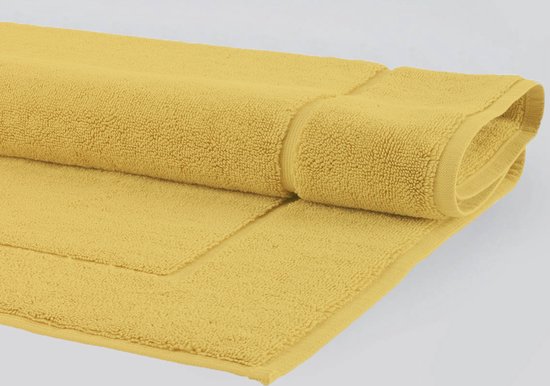Gele badmat, deels opgerold, met zichtbare textuur en een dubbele bies.