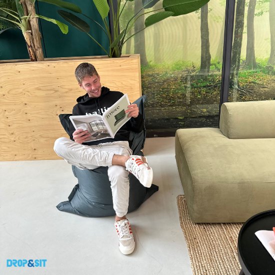 Man zit ontspannen op een donkergrijze zitzak, leest een tijdschrift.