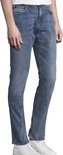 Man met lage taille, staand in een blauwe denim jeans, witte sneakers.