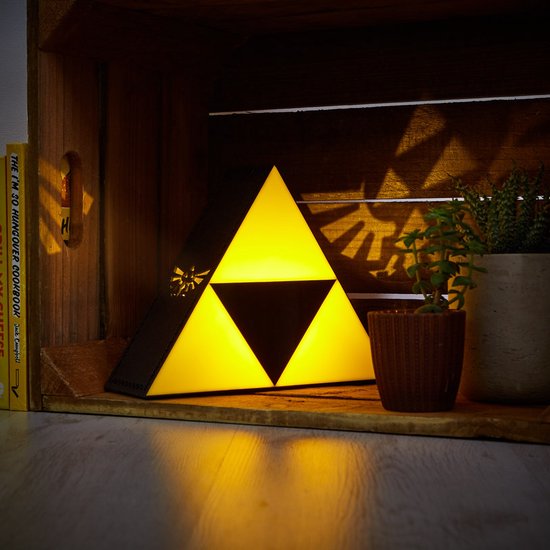 Gele driehoekige lamp met zwart Triforce-symbool en Hylian crest, staat in een houten kist.