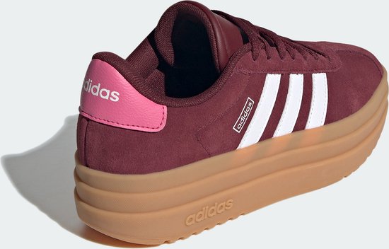Bordeauxrode Adidas sneaker met dikke bruine zool, witte strepen en roze hiel.