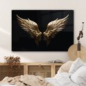 Gouden engelenvleugels op zwarte achtergrond boven een kast in een slaapkamer.