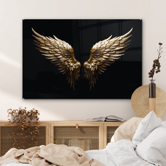 Gouden engelenvleugels op zwarte achtergrond boven een kast in een slaapkamer.