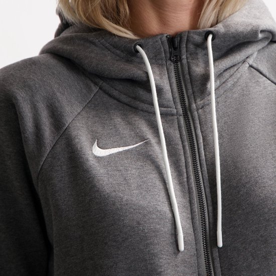 Close-up van de grijze Nike hoodie met rits, capuchon en witte trekkoordjes, met Nike logo op de borst.