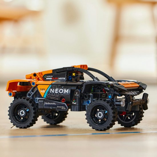 Gedetailleerde LEGO Technic auto, zwart met oranje accenten. Sponsorlogo's zoals 'NEOM' zijn zichtbaar.