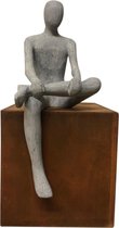 sculptuur man zittend op cortenstaal kubus