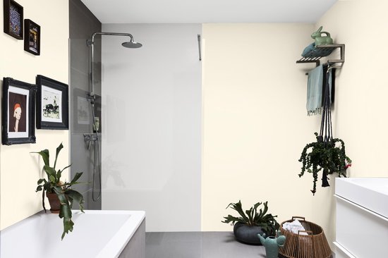 Lichtgekleurde badkamer met ligbad, douche, wastafel en planten op een egale, lichte muur.