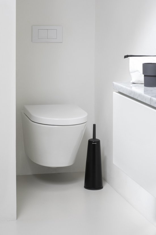 Brosse à toilettes noire avec support dans une salle de bain blanche moderne, à côté de toilettes suspendues.