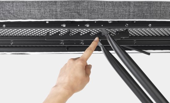 Vingers wijzen naar het zwarte metalen frame en de grijze stof aan de onderkant van de strijkplank.