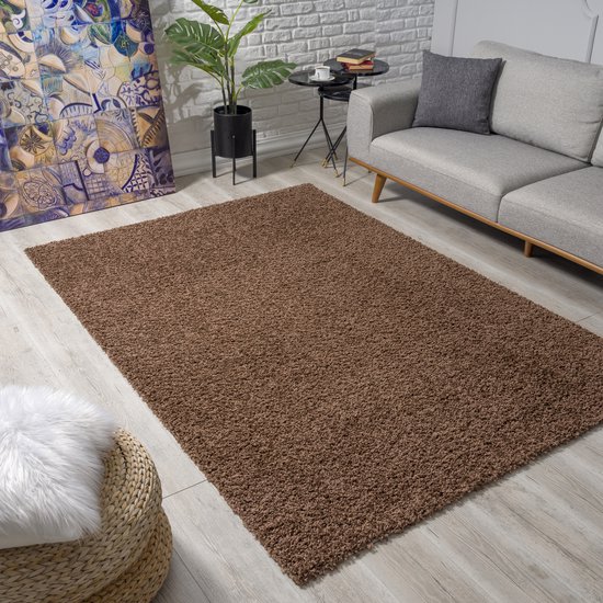 Bruin shaggy vloerkleed in een woonkamer met een grijze bank.