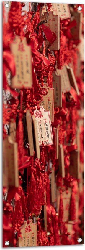 Tuinposter – Rode Sleutelhangers met Chinese Tekens aan een Muur - 40x120 cm Foto op Tuinposter (wanddecoratie voor buiten en binnen)