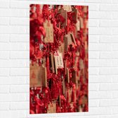 Muursticker - Rode Sleutelhangers met Chinese Tekens aan een Muur - 50x100 cm Foto op Muursticker