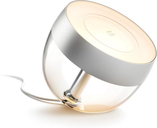 Zilverkleurige Philips Hue Iris tafellamp met glazen kap, die warm wit licht uitstraalt.