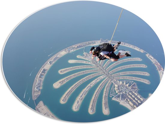 PVC Schuimplaat Ovaal - Parachutespringer boven de Palm van Dubai - 68x51 cm Foto op Ovaal (Met Ophangsysteem)
