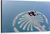 Canvas - Parachutespringer boven de Palm van Dubai - 150x100 cm Foto op Canvas Schilderij (Wanddecoratie op Canvas)
