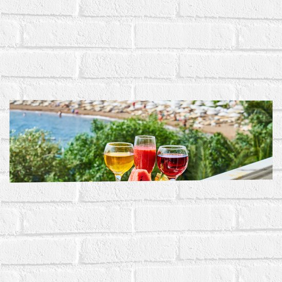 Muursticker - Gekleurde Drankjes met Stukken Fruit en Uitzicht op een Baai - 60x20 cm Foto op Muursticker