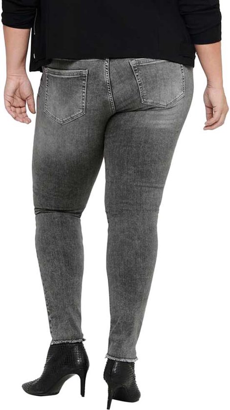 Model van achteren gezien in een zwarte jas en grijze skinny jeans met rafelige zoom.