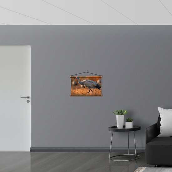 Textielposter - Kraan vogel loopt door natuur gebied heen met zijn groep op de achtergrond - 60x40 cm Foto op Textiel