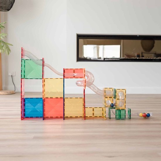 Een grote balrenconstructie van kleurrijke magnetische tegels met doorzichtige buizen, op een houten vloer.