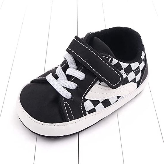 Zwarte babysneaker met witte veters, klittenbandsluiting en schaakbordpatroon.